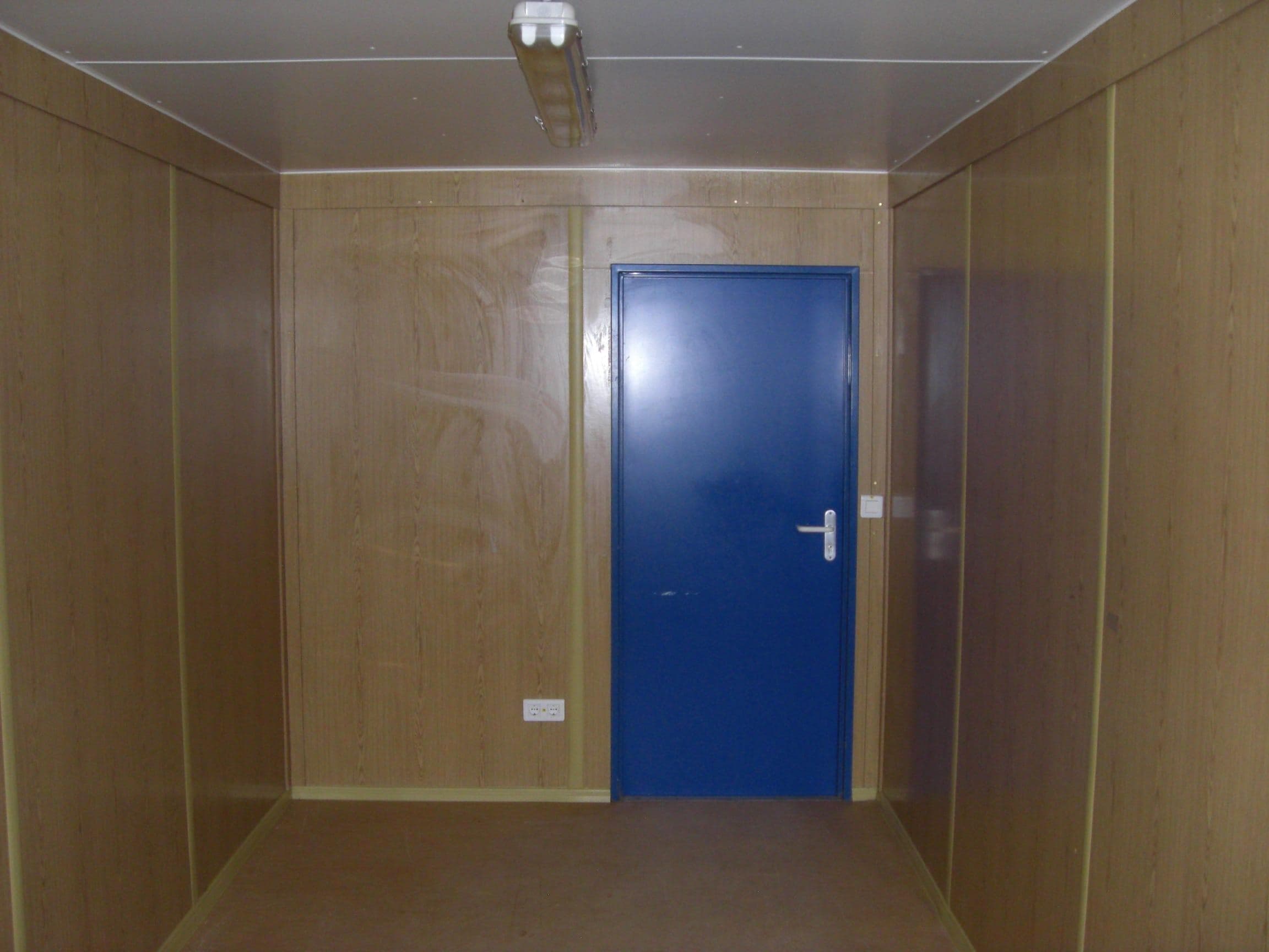 Wohncontainer Innenansicht mit Holzverkleidung und blauer Tür