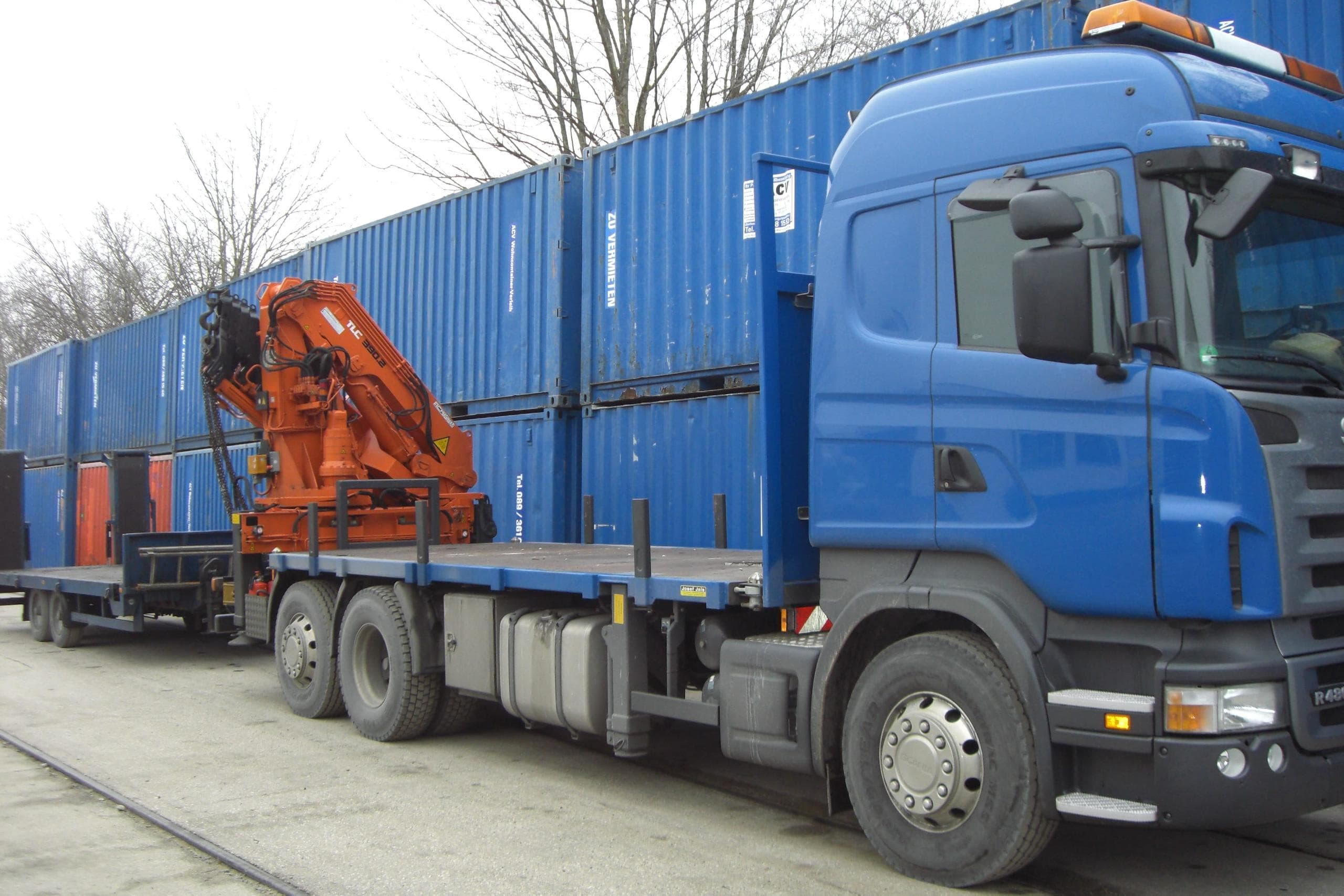 ACV Wohncontainer ausleihen - LKW zur Containerlieferung und blaue Wohncontainer